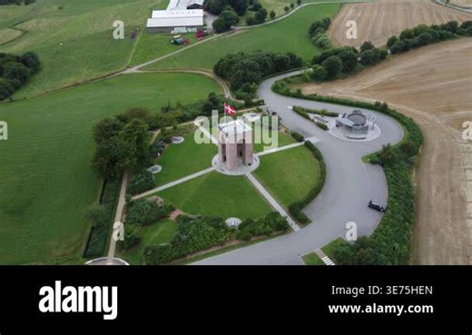 Aerial drone footage of a memorial park near Aarhus, Denmark. Birds-eye view of a brick tower with Danish flag, formal garden with hedged paths, and circular structure, set among green fields and woods. Filmed summer 2022, overcast sky Stock Video Footage - Alamy