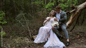 Handsome bride and groom sit cutely on a log in the forest
