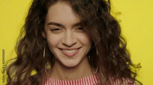 Serious woman laughing in slow motion. Laughing girl looking in camera on yellow