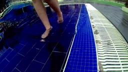 Closeup of feet walking by pool and dipping toe in water. 4K, UHD,...
