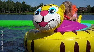 Girl child ride inflatable tiger electric motor boat on pool in amusement park