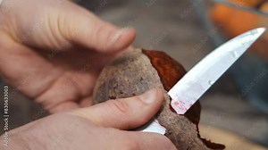 Peeling a root vegetable with a beetroot, Close-up of hands cleaning beets with a knife
