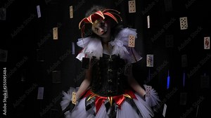Beautiful female jester with makeup and a hat is shaking her head surrounded by floating playing cards
