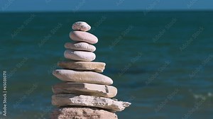 A pyramid of stacked stones by the sea symbolizes balance and harmony in nature, creating a majestic contrast with the blue waves.