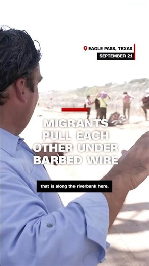 Migrants pull each other under barbed wire