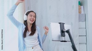 Asian women and beautiful bloggers wear headphones dancing videos by smartphone cameras. Creator vlogger talent dancing enjoys hobby content recording show video sharing on social media.