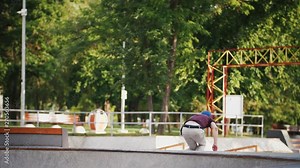 Aggressive Inline roller skater doing tricks in concrete skatepark outdoors with beautiful background, super slow motion