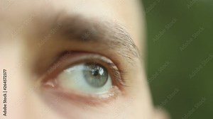 blinking male eye close up. pensive sad look up macro. Half face of a man on a blurred background, front view. red arteries on the eyeball. copyspace.