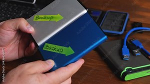 Male hand take external hard drive for back up multimedia files. Save information, data storage and archive database. Laptop on office desk background