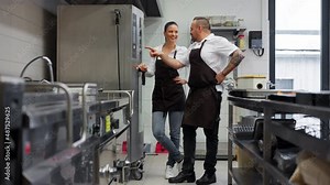 Happy chef and cook working on their dishes indoors in restaurant kitchen.