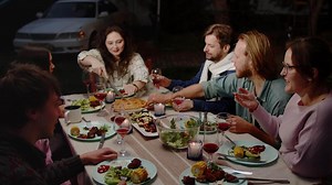 Friends enjoying outdoor dinner party, sharing food and laughter