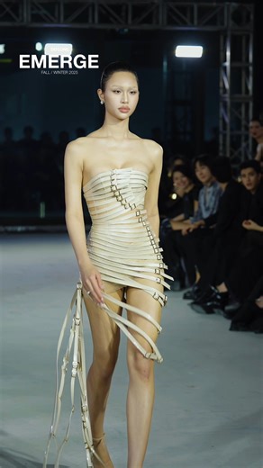 Á hậu Nguyễn Cao Minh Anh xuất hiện trên runway Emerge trong thiết kế Strap Dress màu beige, khai thác vẻ đẹp mạnh mẽ và hiện đại. Trang phục sử dụng chất liệu da simili kết hợp form lưới, toàn bộ được đính dây da và gắn đầu khóa thắt lưng để tạo nên cấu trúc sắc gọn và cá tính. Các đường dây chạy dọc theo thân váy vừa tôn dáng vừa mang lại hiệu ứng thị giác đầy năng lượng. Minh Anh thể hiện phong thái tự tin, sắc lạnh và nổi bật, đúng tinh thần chuyển hóa của Emerge. ____ 1st Runner-up Nguyen C