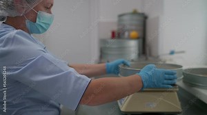 Female worker deals with the grain production at the farm. Producing grain fodder for farmed animals. Placing grain on scales. Producing agricultural food. Farming. Weight measuring