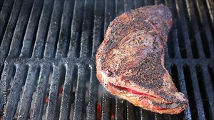 Tri-tip steak cooking on grill with flare ups