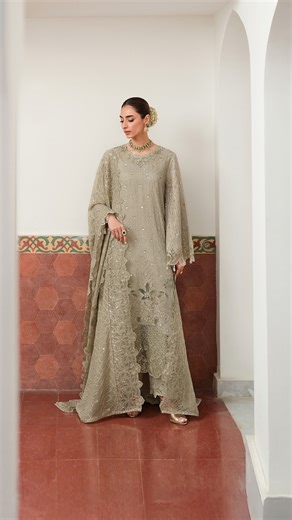 Cross Stitch Studio on Instagram: "Ashen Dream – PKR 45,500 This three-piece ensemble features a loose-fit, panelled silk shirt washed in dyed embroidery across front and back, with traditional adda work tracing the neckline and a softly scalloped hem. Flared sleeves move gently with embroidered tassels, while the matching silk trousers echo the same refined craftsmanship. A flowing chiffon dupatta, finished with delicate tassels, completes a look that feels graceful, poetic, and endlessly refin