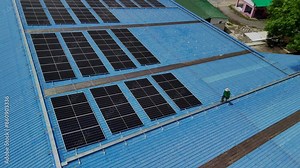 Worker Technicians are working to construct solar panels system on roof. Installing solar photovoltaic panel system. Men technicians carrying photovoltaic solar modules on roof.