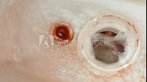 Water flows into the drain hole in the toilet bowl from the tank, inside view. Leaking toilet