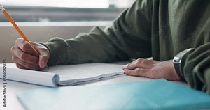 Student, hand and writing on desk for education with learning, development and scholarship in classroom. Closeup, boy and notes for assessment with knowledge, essay summary and studying in academy