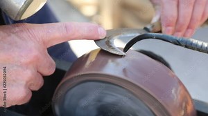 hand of an old man grinds while sharpening his knife billhook blade
