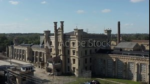 Aerial view of the old and abandoned Joliet prison or jail, a historic site since 1880s. Drone rotating to capture view of front gate. Streets of Naperville Illinois and Joliet Prison.