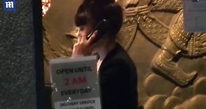 Erika Koike chats on the phone and smokes outside restaurant