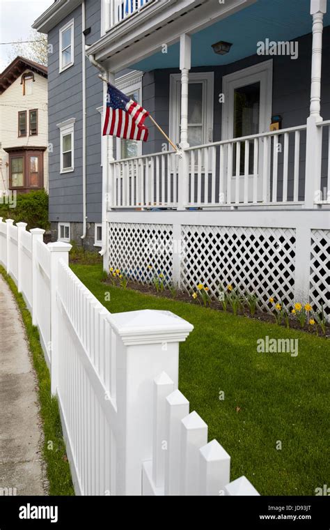 American Flag Flying From Porch Of Wooden House And White Plastic