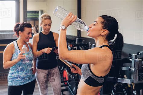 Group Of Women Training In Gym Taking A Break Drinking Bottled Water