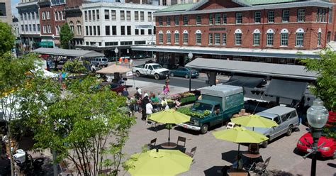 An Outdoor Market With Tables Umbrellas And Cars Parked On The Side Of