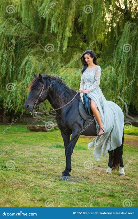 Beautiful Young Woman In Beautiful Dress On Black Horse In Nature Stock