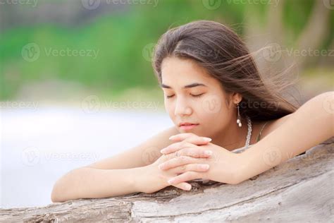 hermosa jovencita en la playa rezando por el registro de madera flotante 963113 foto de stock en