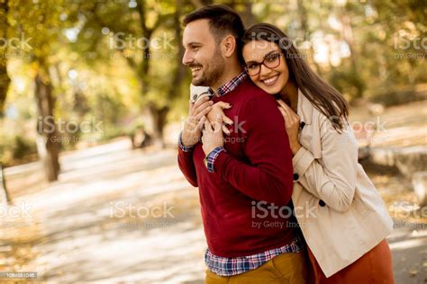 Young Woman And Man Walking In City Park Holding Hands Stock Photo
