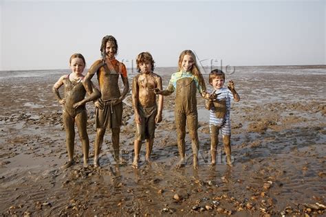 Children covered in mud on rocky beach の写真素材 アフロ