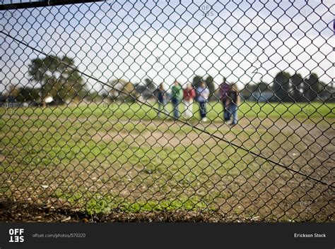 People Standing In A Field Behind A Fence Stock Photo Offset