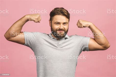 Waistup Portrait Of Muscular Young Man Flexing His Biceps Against Pink