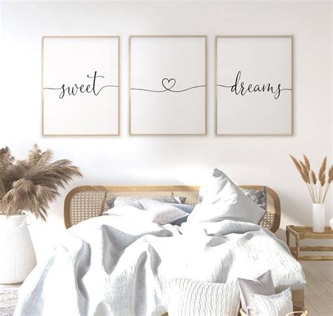 Two Posters On The Wall Above A Bed In A Room With White Walls And Pillows