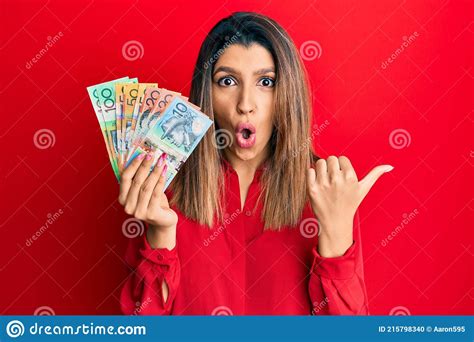 Beautiful Brunette Woman Holding Australian Dollars Surprised Pointing