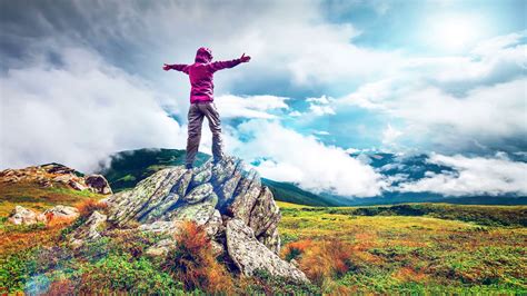 Man standing on the top of the mountain with raised hands. Woman standing on top of a mountain with hands rised up ...