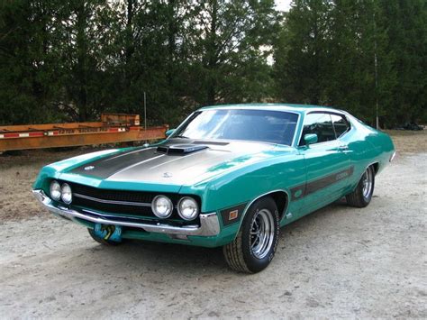 A Green Muscle Car Parked On The Side Of A Dirt Road In Front Of Some Trees