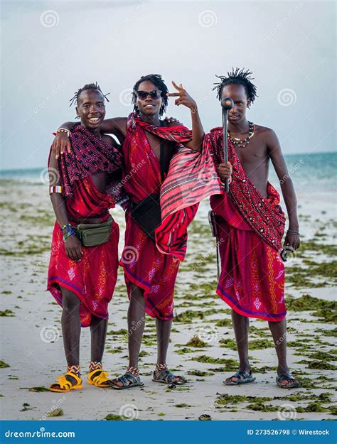 Happy Tanzanian Men In Traditional Clothing On A Sandy Beach Smiling
