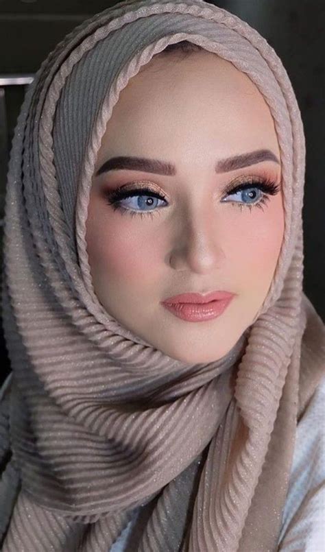 a woman wearing a hijab with blue eyes and pink lipstick on her lips