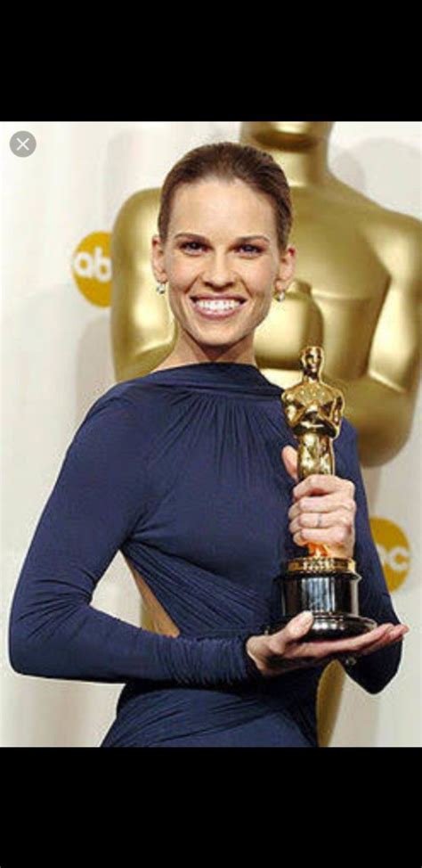 a woman holding an award in her hand and smiling at the camera while wearing a blue dress