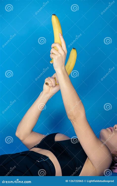 Cropped Image Of Stylish Girl Lying And Holding Bananas In Hands In