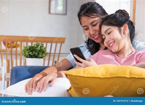 vídeo de observação da lésbica asiática feliz no telefone celular no sofá na casa conceito do