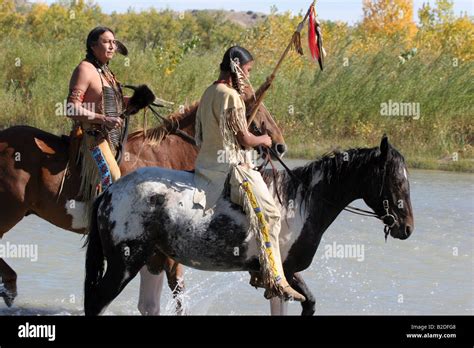 Two Native American Sioux Indian Men On Horseback Walking Through A