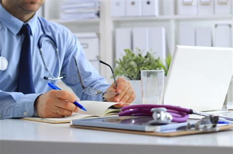 Male Doctor Using A Laptop Sitting At His Desk Stock Photo Image Of