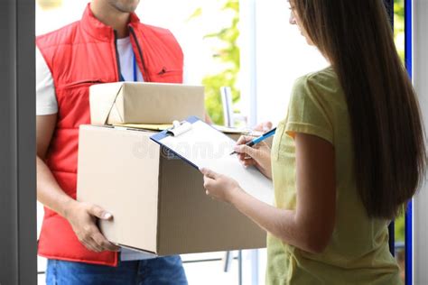 Woman Signing For Delivered Parcels On Doorstep Courier Service Stock