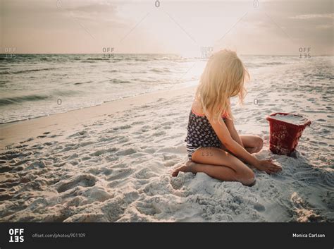 Little Girl Building A Sand Castle On A Beach At Sunset Stock Photo