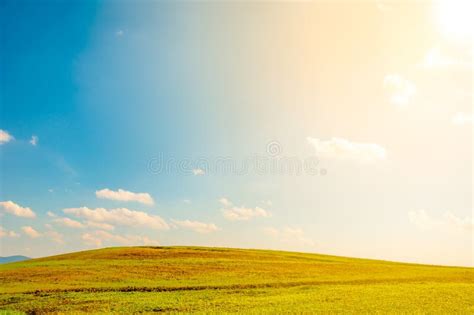 Wide Green Field On Rolling Hills And Blue Sky With Clouds Stock Photo