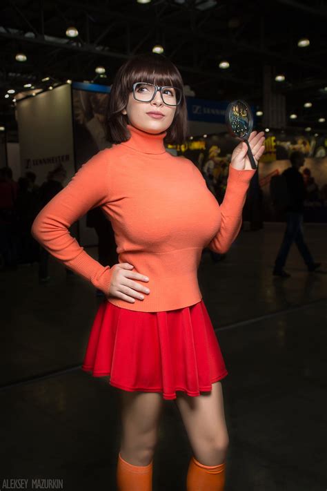 A Woman Dressed In An Orange Sweater And Red Skirt
