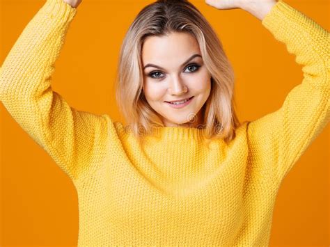 Happy And Cheerful Blonde In A Yellow Sweater On A Yellow Background